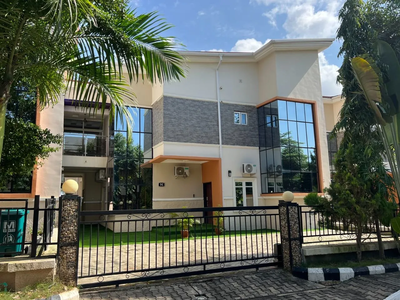 Gated two-storey Four Bedroom Premier house in Apo, Abuja, with palm trees and a paved driveway